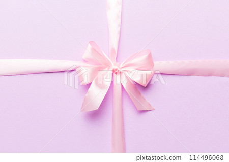 Top view of purple ribbon rolled and pink bow isolated on colored background. Flat lay with copy space 114496068
