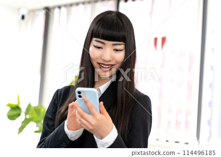 Female employee using a smartphone Female employee using a smartphone 114496185