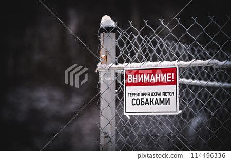A sign on the fence with the Russian inscription "Attention! The territory is guarded by dogs" A sign on the fence with the Russian inscription "Attention! The territory is guarded by dogs" 114496336
