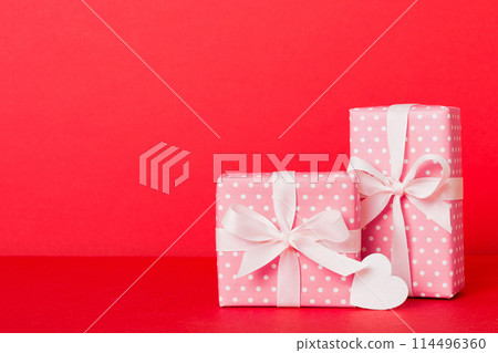 gift box with red bow and red heart on colored background. Perspective view. Flat lay gift box with red bow and red heart on colored background. Perspective view. Flat lay 114496360
