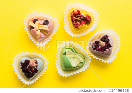 chocolate sweets in the form of a heart with fruits and nuts on a colored background. top view with space for text, holiday concept 114496368