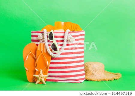 Stylish bag with beach accessories . Summer holiday concept. beach bag with straw hat with space for text Stylish bag with beach accessories . Summer holiday concept. beach bag with straw hat with space for text 114497119