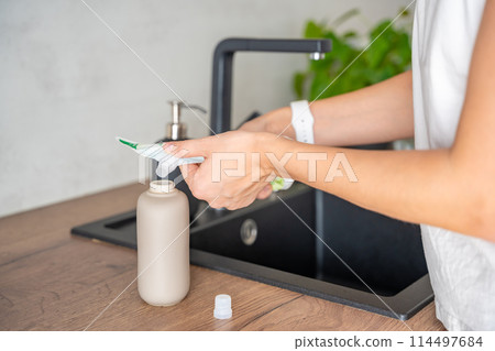 A woman pours soap or detergent from recycled packaging into a reusable bottle. Eco-friendly lifestyle concept A woman pours soap or detergent from recycled packaging into a reusable bottle. Eco-friendly lifestyle concept 114497684