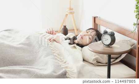 Woman sleeping with alarm clock set Woman sleeping with alarm clock set 114497805