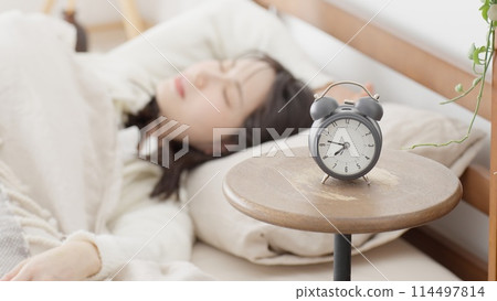 A woman who turns off the alarm and goes back to sleep 114497814