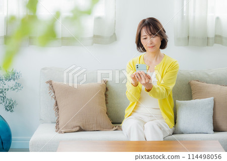 A middle-aged woman operating a smartphone 114498056
