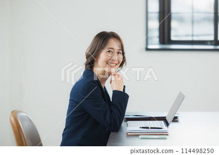 Middle-aged business woman working on a laptop Middle-aged business woman working on a laptop 114498250