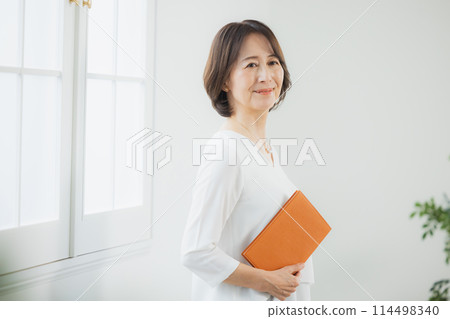Middle-aged woman working remotely 114498340