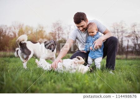 Father and little toddler boy playing with dogs, having fun during warm spring day. Father's day concept. Family time outdoors. Father and little toddler boy playing with dogs, having fun during warm spring day. Father's day concept. Family time outdoors. 114498676