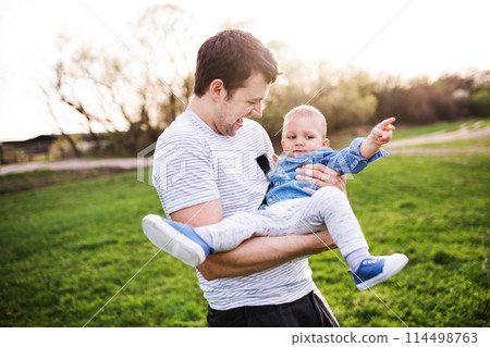 Father holding little toddler boy playing, having fun during warm spring day. Father's day concept. 114498763