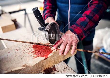 Sawing into finger with circular saw. Injured worker with wound hand. Work injury, accident in workplace. Sawing into finger with circular saw. Injured worker with wound hand. Work injury, accident in workplace. 114498944