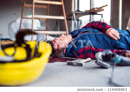 An unconscious man worker lying on the floor after a head injury. Work injury, accident in workplace. 114498963