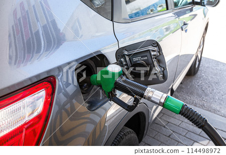 Passenger car is refueled at a gas station. Gasoline pump gun to release fuel Passenger car is refueled at a gas station. Gasoline pump gun to release fuel 114498972