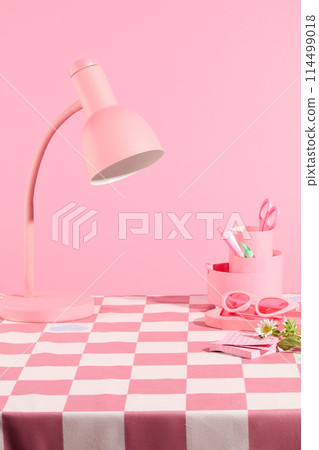 A table with checkered pink table cloth over pastel pink background, containing a lamp and some pink accessories above. Blank space for displaying product, front view A table with checkered pink table cloth over pastel pink background, containing a lamp and some pink accessories above. Blank space for displaying product, front view 114499018