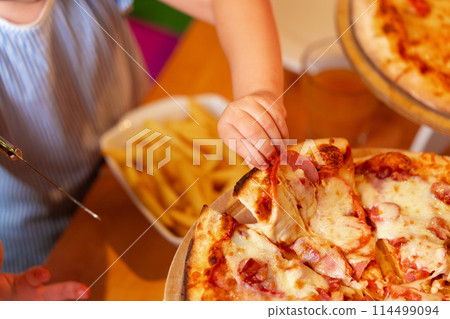 Young Girl Enjoying a Slice of Pizza at a Birthday Party Indoors Young Girl Enjoying a Slice of Pizza at a Birthday Party Indoors 114499094