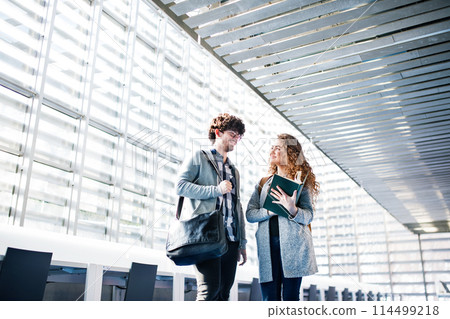 Young university students studying togeter in library, talking, preparing for final exam. Study group. Teamwork skills. 114499218
