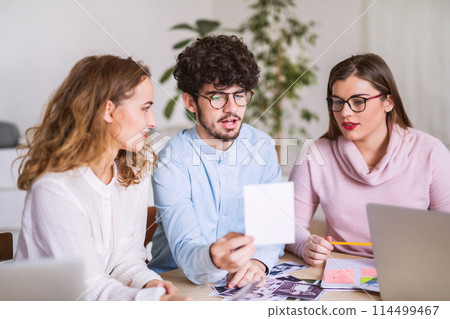 Young group of colleagues working on a new project together in a startup company office. Working in co-working space. 114499467