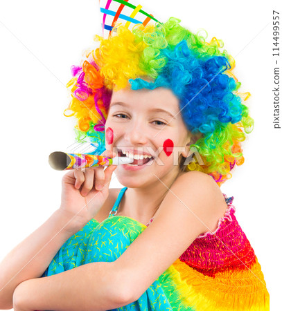 Cheerful young little girl in curly clown wig and party horn blower isolated on white background 114499557