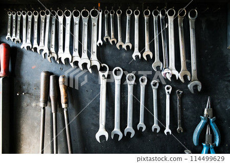 Combination wrenches set in auto repair shop. Mechanics repairing, maintaining car in garage. 114499629