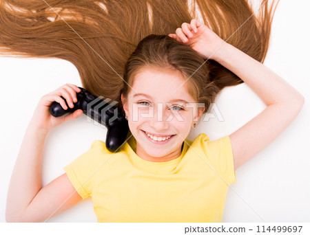 Smiling girl stretching on the floor with joystick in hand, tired after playing computer games Smiling girl stretching on the floor with joystick in hand, tired after playing computer games 114499697