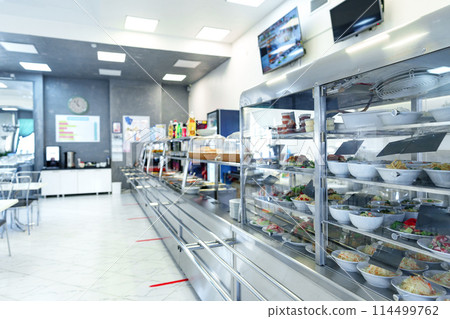 Bustling Cafeteria Serving Line During Lunchtime Offering a Variety of Dishes 114499762