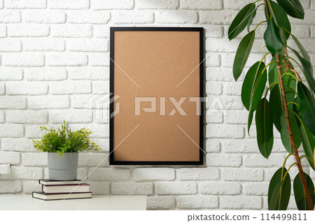 Blank Photo Frame on White Brick Wall With Houseplants and Books 114499811