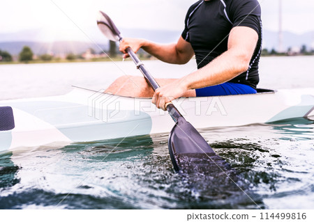Canoeist man sitting in canoe holding paddle, in water. Concept of canoeing as dynamic and adventurous sport. Rear view, sportman looking at water surface, paddling 114499816
