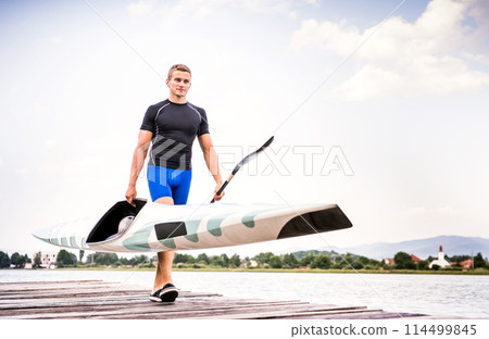Young canoeist carry canoe and paddle, going into water, walking on wooden dock. Concept of canoeing as dynamic and adventurous sport 114499845
