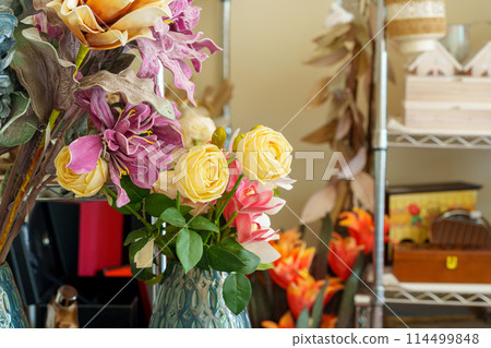 Vibrant Assortment of Artificial Flowers in a Vase Inside a Cozy Craft Room 114499848