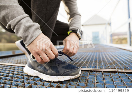 Close up of running sneakers dirty after run in spring nature. Tying shoelaces. 114499859