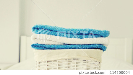 Wicker laundry basket with clean folded towels on the bed Wicker laundry basket with clean folded towels on the bed 114500004