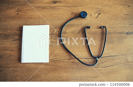 Medical stethoscope and white blank notebook for copy space text on wooden table, top view 114500006