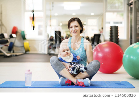 Portrait of new mom on group exercise class in gym. Moms staying active while boding with babies. 114500020