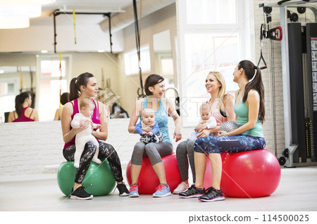 Baby movement class. Parents helping babies to improve motor skills, proper movement on fitball. Pediatric physical therapist leading class. Mothers exercising with babies. Baby movement class. Parents helping babies to improve motor skills, proper movement on fitball. Pediatric physical therapist leading class. Mothers exercising with babies. 114500025