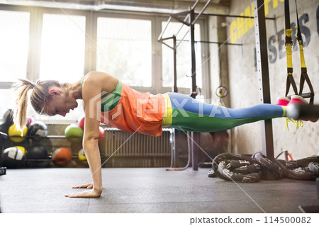 Beautiful sport woman doing suspension training, total resistance exercise. Routine workout for woman's physical and mental health. 114500082
