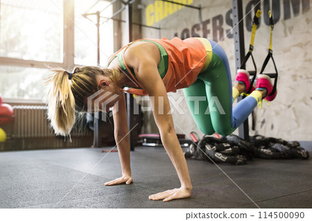 Beautiful sport woman doing suspension training, total resistance exercise. Routine workout for woman's physical and mental health. 114500090