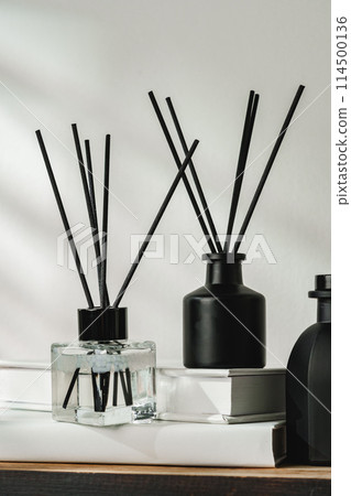 Aromatic Reed Diffuser on White Books With Shadows Playing on the Wall Aromatic Reed Diffuser on White Books With Shadows Playing on the Wall 114500136