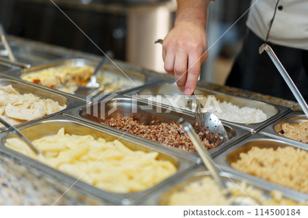 Chef Serving Freshly Cooked Dishes at a Restaurant Buffet During Lunchtime Chef Serving Freshly Cooked Dishes at a Restaurant Buffet During Lunchtime 114500184