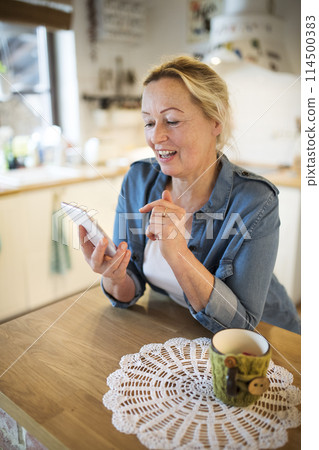 Beautiful mature woman at home, texting with friends. Older woman living alone, enjoying peaceful weekend day 114500383