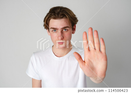Young Man in White T-Shirt Showing Stop Gesture With Hand Young Man in White T-Shirt Showing Stop Gesture With Hand 114500423
