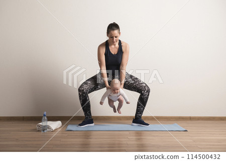 Home exercise for mother and baby, mommy and me workout. Using the baby's weight to perform squats 114500432