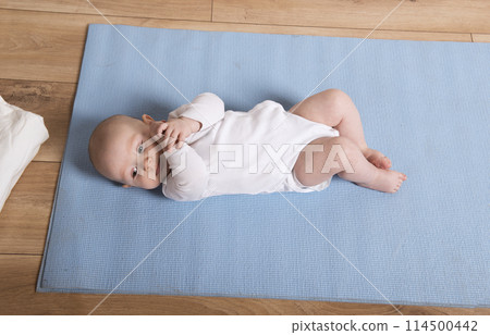 Portrait of an adorable baby lying on a mat on the floor, looking at the camera and smiling. Portrait of an adorable baby lying on a mat on the floor, looking at the camera and smiling. 114500442