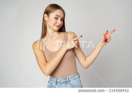 Young Woman in Tank Top Pointing at Something on gray background Young Woman in Tank Top Pointing at Something on gray background 114500452
