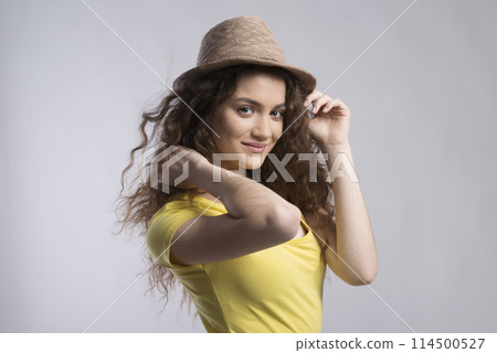 Portrait of a gorgeous teenage girl with curly hair and hat. Studio shot, white background with copy space Portrait of a gorgeous teenage girl with curly hair and hat. Studio shot, white background with copy space 114500527