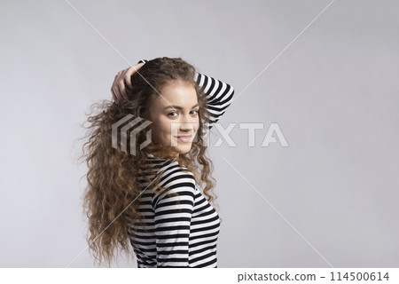 Portrait of a gorgeous teenage girl with curly hair. Studio shot, white background with copy space 114500614