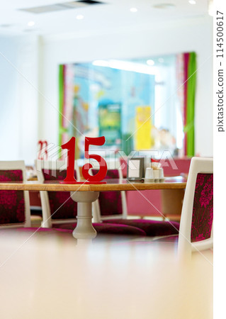 Vibrant Restaurant Interior With Red Number 15 on Table and Colorful Artwork in Background Vibrant Restaurant Interior With Red Number 15 on Table and Colorful Artwork in Background 114500617