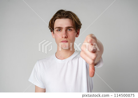 Young Man Giving a Thumbs Down Gesture Against a White Background Young Man Giving a Thumbs Down Gesture Against a White Background 114500875