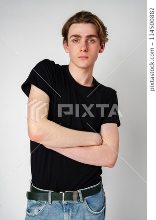 Young Man With Brown Hair Wearing Black T-Shirt Posing Against a White Background Young Man With Brown Hair Wearing Black T-Shirt Posing Against a White Background 114500882