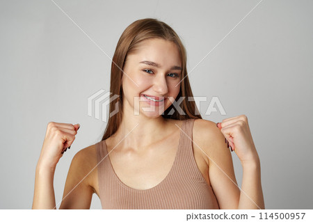 Young woman standing with her arms lifted high above her head expressing joy and triumph 114500957