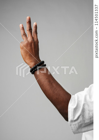 Human Hand Gesturing Three Fingers Up Against a Neutral Grey Background 114501337